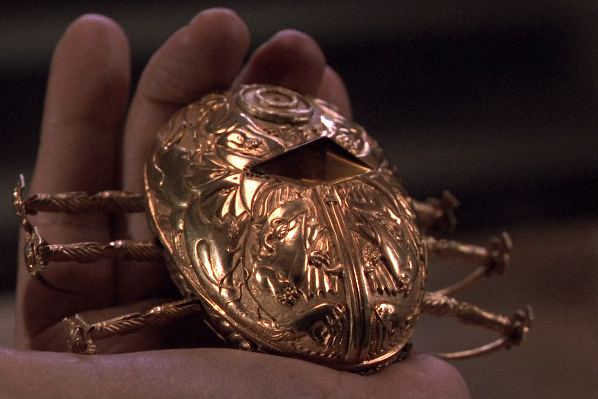 A gleaming golden mechanical scarab held in a man’s hand in Guillermo del Toro’s horror movie Cronos
