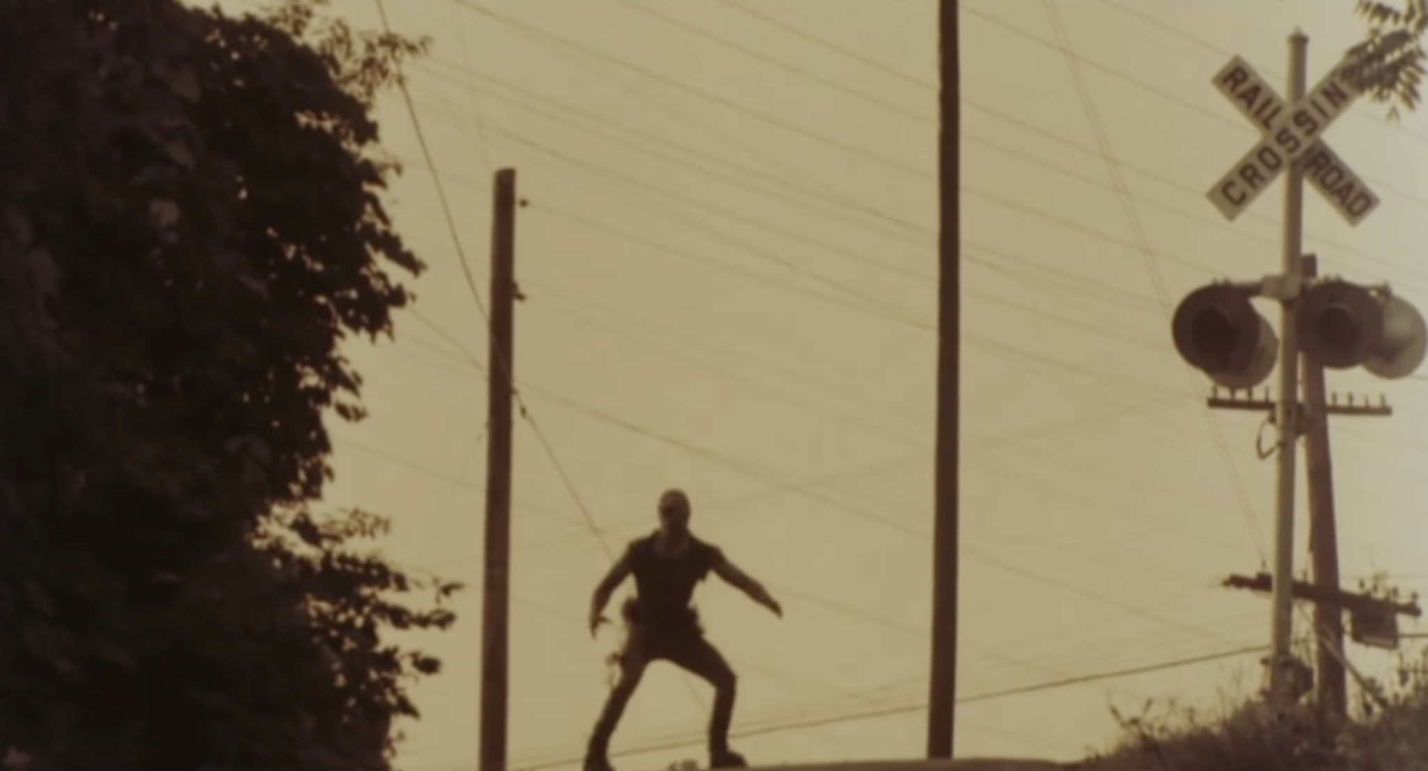 The Toxic Avenger’s silhouette stands menacingly on the street as the sun sets.